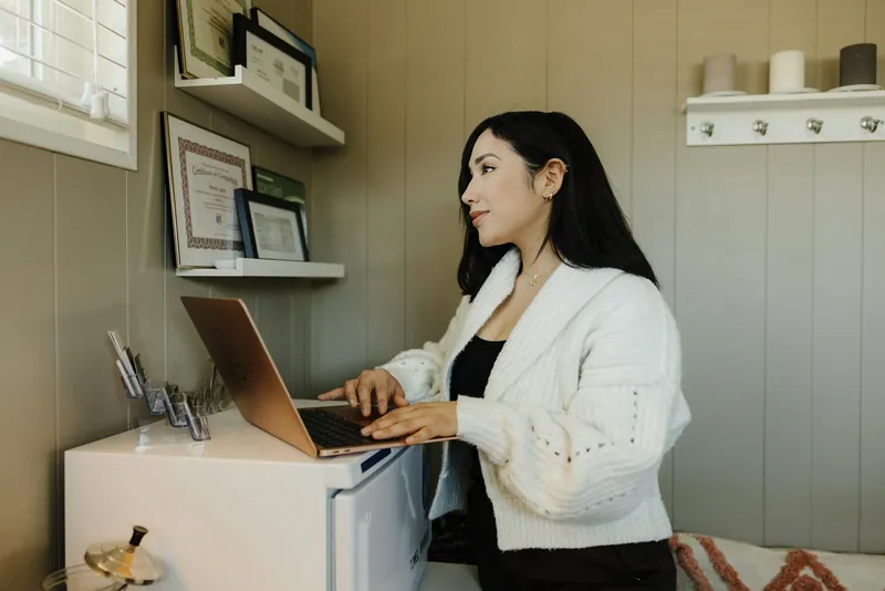 A business owner working at a laptop, standing in her shop